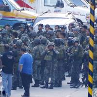 Philippine National Police Special Action Forces prepare to enter the Resorts World Manila complex in suburban Pasay city, southeast of Manila, Friday. A masked gunman stormed the hotel-casino complex early Friday, shooting up a TV screen, torching gambling tables and stuffing a backpack with casino chips before fleeing, authorities said. Gunman kills himself after causing panic in apparent robbery attempt and torching of Manila casino