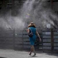 A woman walks along a row of misters Monday in Tempe, Arizona. The forecast calls for a high of 118 on Monday and 120 on Tuesday in Phoenix. Southwestern U.S. braces for rare heat wave dangerous to health, aircraft