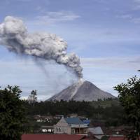 Mount Sinabung spews volcanic ash into the air, as seen from Berastagi, North Sumatra, Indonesia, Monday. Search continues for German hiker missing five days on dormant Indonesia volcano