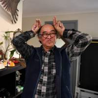 Philip Fok and his wife, Josephine, migrants from Hong Kong, reminisce over a photo of Philip in his younger days as a mime artist in Hong Kong, at their home in Sydney on May 30. Looking back: The Hong Kongers who left