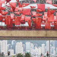 The flags of China and Hong Kong fly beside an outdoor walkway connecting two buildings in Hong Kong on Tuesday. Ahead of 20th anniversary of Hong Kong's handover from Britain, Beijing loyalists baffled, youths ever more alienated