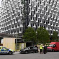 Police stand beside two vehicles in which they carried out controlled explosions near the new but still unoccupied U.S. Embassy building in south London Wednesday. Police carried the conrolled explosions after being called to a report of two unattended vehicles. London police conduct controlled explosion near new U.S. Embassy, rule out terrorism