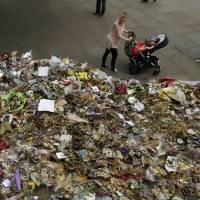 A woman and a young child look at floral tributes Tuesday near the southern end of London Bridge, the scene of a June 3 terrorist attack. London copes with deep divisions after enduring three attacks, tower fire