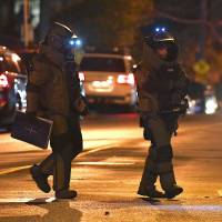 Australian police from the bomb squad unit walk near the site where a gunman was shot dead after holding a woman hostage in Melbourne, Australia, Monday. Islamic State takes credit for Melbourne hostage incident