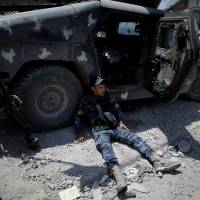 A member of the Iraqi Federal police rests next to an armored vehicle at the frontline in western Mosul, Iraq, Sunday. Civilians able to flee Islamic State-held homes in Mosul count their blessings as fighting intensifies