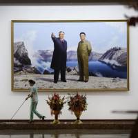 A hotel staff member mops the floor near a picture featuring portraits of late North Korean leaders Kim Il Sung (left) and Kim Jong Il in Pyongyang on Monday. After Warmbier death, U.S. weighs ban on travel to North Korea