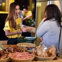 A volunteer helps a customer at OzHarvest Market in Sydney on May 10. Australia opens war on food waste