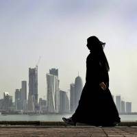 A Qatari woman walks in front of the city skyline in the capital, Doha, in 2010. Qatar crisis: Solution seems far off after demands aired