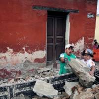 A municipal worker and a firefighter (right) remove debris from a damaged house after an earthquake in Antigua, Guatemala, Thursday. Strong M6.8 temblor hurts four, causes damage in Guatemala
