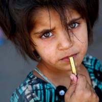 A Syrian girl who fled areas under the Islamic State (IS) group control in Raqqa, is seen posing with a bullet cartridge in her hand on Tuesday in the suburb of Jazra on the western city limits of Raqqa after the area was seized by Syrian Democratic Forces (SDF) from the jihadis. Free to roam, kids finding ways to help families survive, flee Islamic State fighters in Raqqa