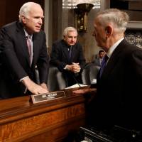 U.S. Defense Secretary James Mattis greets Sen. John McCain (R-AZ) and Sen. Jack Reed (D-RI) prior to testifying before the Senate Armed Services Committee on Capitol Hill in Washington Tuesday. U.S. Senate overwhelmingly votes for new sanctions on Russia over poll meddling and limits Trump's ability to lift them