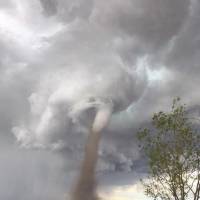 In this Friday photo provided by Cecilia Wessels via The Canadian Press, Theunis Wessels mows his lawn at his home in Three Hills, Alberta, as a tornado swirls in the background. Cecilia Wessels, who took the image of her husband to show the tornado to her parents in South Africa, said that the twister wasn’t as close it appears. Photo of Canadian man mowing lawn with tornado behind him causes social media storm
