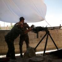 A Kurdish fighter from the People’s Protection Units (YPG) fires a heavy machine-gun at Islamic State militants in Raqqa, Syria, Wednesday. Turkey sends reinforcements into northern Syria to fight Kurds, rebel allies