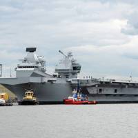 Tug boats maneuver the 65,000-ton British aircraft carrier HMS Queen Elizabeth on the Firth of Forth in east Scotland Monday after escorting it out of its berth in Rosyth Naval dockyard to begin sea trials. U.K.'s new, and only, aircraft carrier readies for maiden voyage