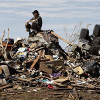 A resident sits atop his destroyed home in May 2013 after a huge tornado roared through the Oklahoma City suburb of Moore. More effects of extreme weather in form of heat waves, heavy rains recorded