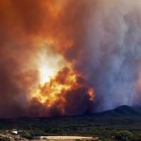 In this Tuesday frame from video, flames and smoke rise from a fire near Mayer, Arizona. The Arizona fire forced the evacuation of Mayer along with several other mountain communities in the area. Thousands flee their homes as Arizona wildfire rages through forest