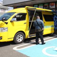 A Banco do Brasil customer waits for his turn at the bank’s mobile service van in front of a Brazilian supermarket in Oizumi, Gunma Prefecture, on April 2. Roving vans serve Japanese-Brazilian community's banking, food and other needs