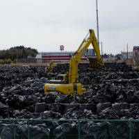 An excavator sits among bags of nuclear waste in the town of Tomioka near the Fukushima No. 1 nuclear plant in March 2016. Court finds ex-environment ministry official Yuji Suzuki guilty of taking bribes
