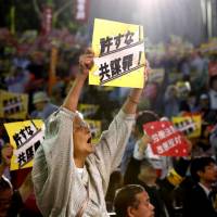 Protestors hold up signs in a demonstration opposing the conspiracy bill in Tokyo’s Hibiya Park on May 24. Some are concerned that the bill does not set a limit on police investigation methods. One-time informant, arrested after working with police, sounds alarm on conspiracy bill