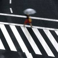 A woman walks on a pedestrian crossing in the rain Wednesday n Tokyo. Evacuation advisories issued as heavy rain drenches wide swaths of Japan