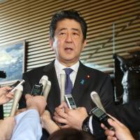 Prime Minister Shinzo Abe speaks to journalists at his office in Tokyo on Thursday. Abe plans to reshuffle Cabinet, LDP leadership to ease public anger over Kake scandal, conspiracy bill