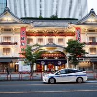 A Toyota Prius hybrid taxi drives past a kabuki theater in Tokyo on Tuesday. Toyota abandons electric vehicle tie-up with Tesla