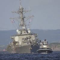 The damaged USS Fitzgerald is towed by a tugboat in the waters near the U.S. Naval base in Yokosuka on Saturday after it collided with the Philippine-registered cargo ship ACX Crystal in the waters off the Izu Peninsula. USS Fitzgerald crash site off Japan known for congested nighttime traffic