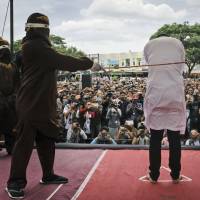 A Shariah law official whips one of two men convicted of gay sex during a public caning outside a mosque in Banda Aceh, the capital of Indonesia’s Aceh province. Asia lags Taiwan in accepting LGBTQ equality