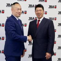 Japan Basketball Association technical director Tomoya Higashino (left) and new men’s national team assistant coach Kenichi Sako pose for photos at a news conference at the JBA office on Friday. Prolific winner Sako, a JBL legend, joins national team coaching staff