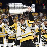 Pittsburgh’s Sidney Crosby lifts the Stanley Cup as the rest of the Penguins celebrate behind him on Sunday in Nashville, Tennessee. Penguins repeat as Stanley Cup champions