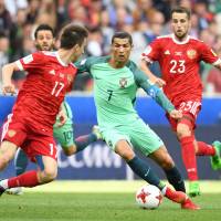 Portugal’s Cristiano Ronaldo (center) and Russia’s Alexander Golovin (left) and Dmitriy Kombarov vie for the ball in a Confederations Cup Group A match on Wednesday in Moscow. Superstar Ronaldo steers Portugal past Russia
