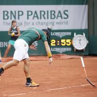 Kei Nishikori slams down his racket during his third-round match against Hyeon Chung at the French Open on Saturday in Paris. Nishikori's match stopped by rain