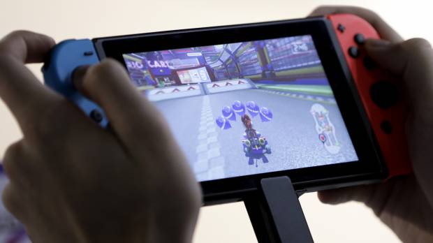 A person plays Nintendo’s “Mario Kart 8 Deluxe” video game on a Switch console. With Switch, Nintendo seen enticing players to use just one device