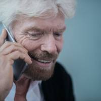 Billionaire Richard Branson, founder of Virgin Group Ltd., speaks on a smartphone during an interview in Hong Kong on Wednesday. Virgin Galactic will conduct powered flights with new SpaceShipTwo craft roughly every three weeks after its restart, Branson said in the interview. Branson ready to resume powered flights of rocket plane, eyes 2018 trip to space