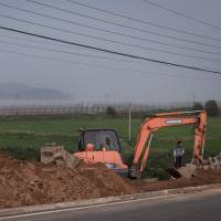 North Korea looms in the distance as a man stands next to a backhoe on the side of a road near the Demilitarized Zone on the island of Ganghwa, west of Seoul, on Tuesday. North Korean defectors down as reclusive nation tightens grip on border, Seoul says