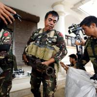 Philippines troops store seized combat weapons in bags after a news conference, as government soldiers continue their assault on insurgents from the Maute group in Marawi, Philippines, on Tuesday. Philippines' top court upholds Duterte's martial law declaration