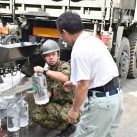 A member of the 4th division of the Japan Ground Self-Defense Forces offers water to a resident on Tuesday following heavy flooding in Asakura, Fukuoka Prefecture. Scientists conducted an experiment with 50 people at a lab in Zurich who reported on their happiness levels after acts of generosity. Giving creates happiness, study finds