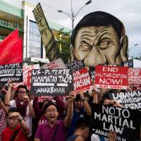 Protesters gather outside the Philippine House of Representatives in Quezon City where President Rodrigo Duterte delivered his second state of the nation address Monday. Duterte says Manila and Beijing in talks for joint exploration of South China Sea