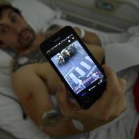 Bill Hillmann shows a photo of himself that someone sent to him during a bull run a day before he was gored at the San Fermin bull running festival, in Pamplona, Spain, on Saturday. Gored at Pamplona bull run, man promises to run again