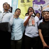Opposition lawmakers Edward Yiu (from left to right), Nathan Law, Leung Kwok-hung and Lau Siu-lai protest a ruling outside the High Court in Hong Kong on Friday. Protesters gather after Hong Kong's High Court disqualifies four lawmakers from parliament