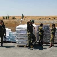 Israeli soldiers stand next to food supplies being prepared for Syrian refugees at an army base in the Israeli-annexed Golan Heights and Syria, on Wednesday. Israel is planning for a new field hospital to treat patients from the civil war-hit country, on the Syrian side of the fence but on the Israeli side of the demarcation line in the Golan Heights. Israel military providing comprehensive humanitarian aid for victims of Syria's civil war
