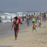 A lifeguard patrols the crowded shoreline at Manhattan Beach, California, on Saturday. Crowds flocked to Southern California beaches to escape triple-digit heat inland. An excessive heat wave in Southern California set records in several cities, breaking a mark set for the date in Los Angeles 131 years ago, the National Weather Service said. Power back after widespread Los Angeles blackout amid heat wave