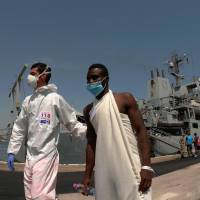 An Italian paramedic helps a migrant during the disembarcation of 402 migrants from the Britain Royal Navy’s ship Echo in the harbor of Brindisi, Italy, Friday. Italy urges EU ports to take migrants as influx soars but NGO boats cool to comply