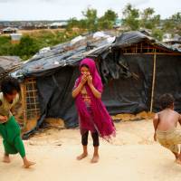 A Rohingya refugee girl reacts to the camera while two other children play marbles at the Kutupalang Makeshift Refugee Camp in Cox’s Bazar, Bangladesh, Saturday. UNHCR chief: Rohingya refugees face lengthy stay in squalid Bangladesh camps amid 'dire state' in Rakhine