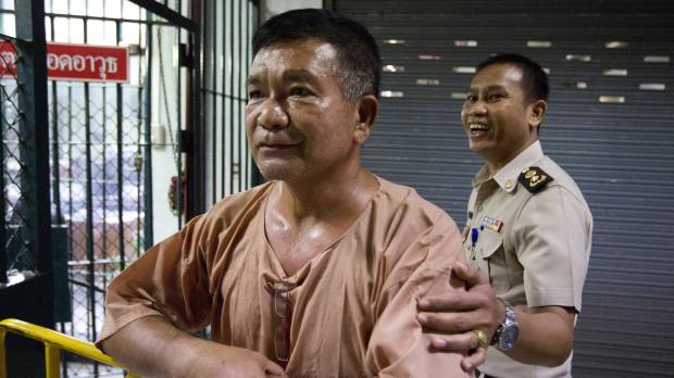 Lt. Gen. Manas Kongpaen of the Royal Thai Army is escorted by a Thai correction officer on his arrival last year at the Criminal Court in Bangkok. The Thai army general was one of the most prominent figures found guilty Wednesday in a major human trafficking trial that included more than 103 defendants accused of involvement in a modern-day slave trade. Thailand convicts 62 in trafficking case, after more than 30 bodies — believed to be Rohingya — were found