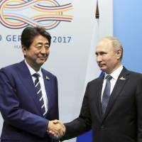 Prime Minister Shinzo Abe greets Russian President Vladimir Putin before their talks on Friday, the first day of the Group of 20 summit in Hamburg, Germany. Abe, Putin to step up talks on joint economic activities on disputed Russian-held isles