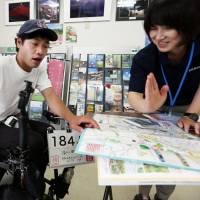 Yusuke Terada (left) asks for information at a tourism information center in Gotemba, Shizuoka Prefecture. Man travels by wheelchair through Japan, propelled by the kindness of strangers