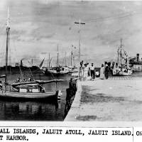 This undated photo discovered in the U.S. National Archives by Les Kinney shows people on a dock in Jaluit Atoll, Marshall Islands. A new documentary film proposes that this image shows aviator Amelia Earhart (seated third from right) gazing at what may be her crippled aircraft loaded on a barge. The documentary “Amelia Earhart: The Lost Evidence,” which aired Sunday on the History channel, argues that Earhart and her navigator, Fred Noonan, crash-landed in the Japanese-held Marshall Islands, were picked up by Japanese military and that Earhart was taken prisoner. Japanese blogger challenges photo key to new Earhart theory
