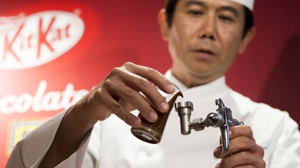 Yasumasa Takagi, owner and head chef of Le Patissier Takagi, pours liquid chocolate into an airbrush during a media preview of the Kit Kat Chocolatory Ginza store in Tokyo on Monday. From wasabi to raspberry, Japan's exotic Kit Kat varieties a sure win with tourists
