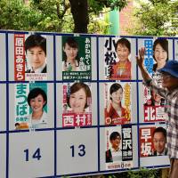 A man walks by election posters in Suginami Ward, Tokyo, on Sunday. Many voters approached by The Japan Times said they were turned off by the Liberal Democratic Party’s scandals but were uncertain about the goals of Tokyo Gov. Yuriko Koike’s upstart party Tomin First no Kai. Despite vague platform, Tomin First outshining status quo in Tokyo